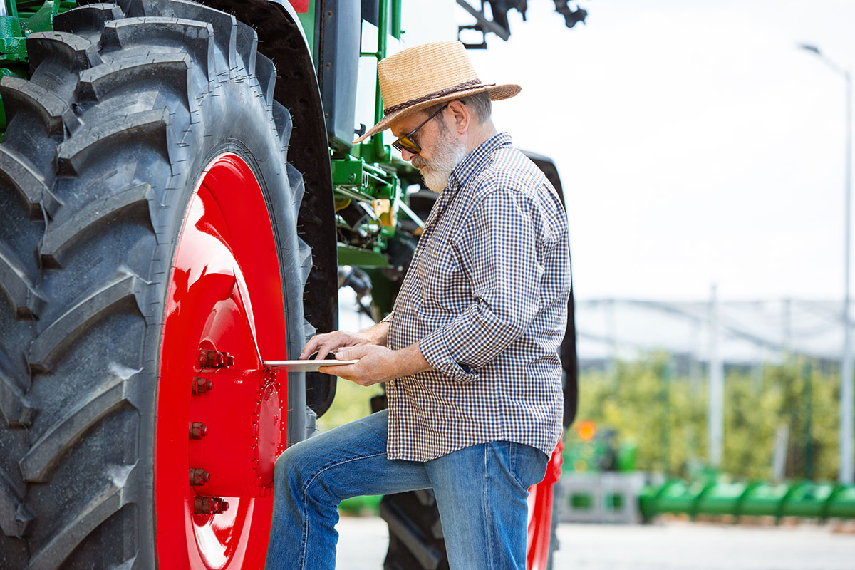 agriculteur devant son tracteur avec une tablette connectée